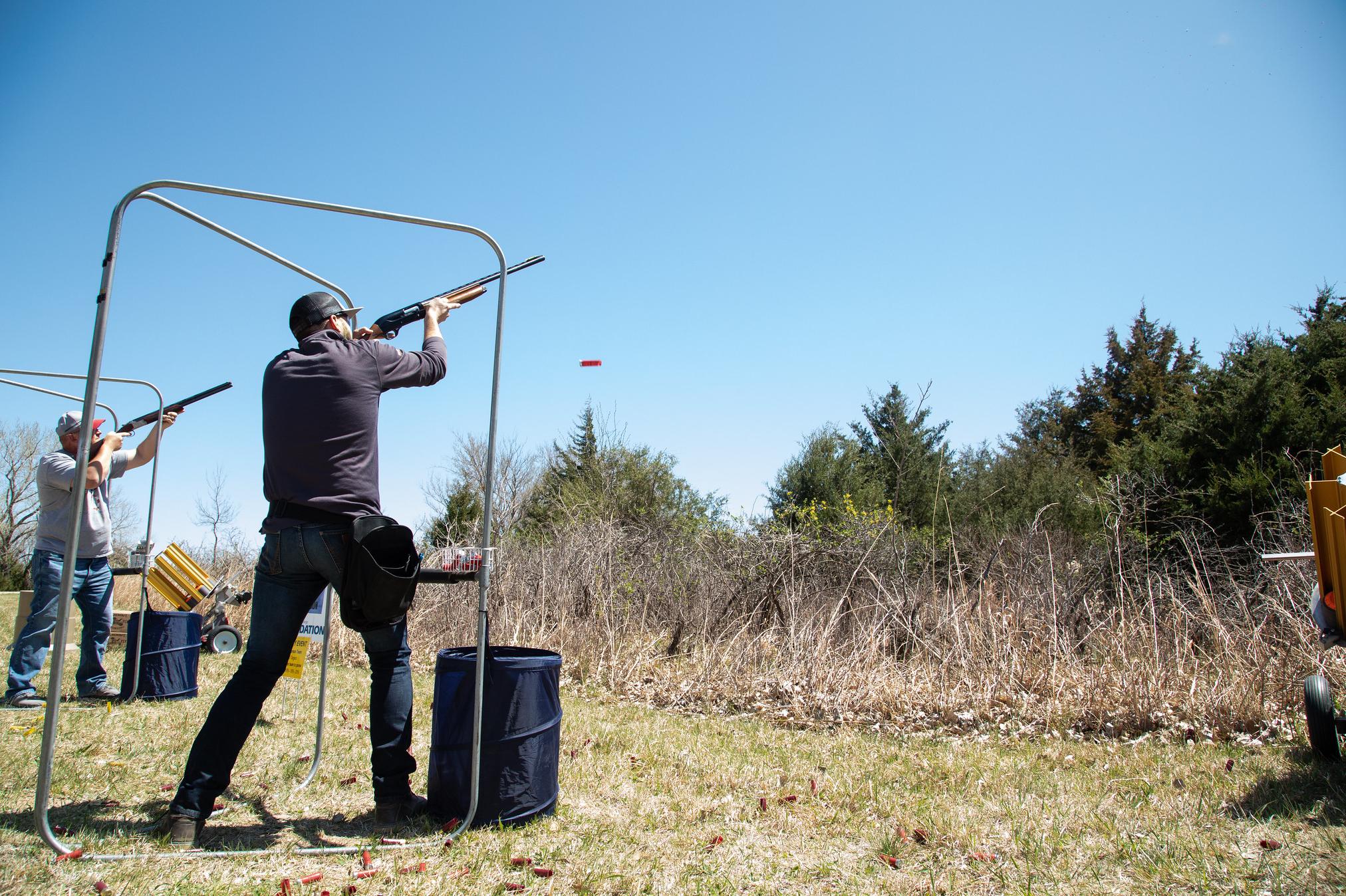 two people shooting shotguns at clay targets in a country landscape type area